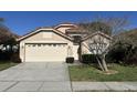 Two-story house featuring a tan exterior, double garage, and a tree at 5453 Shingle Creek Dr, Orlando, FL 32821