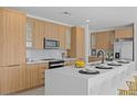 Modern kitchen with light wood cabinets, quartz countertops, and island seating at 6491 Octave St, Mascotte, FL 34753