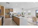 Open-concept kitchen with island, stainless steel appliances, and views into living room at 6491 Octave St, Mascotte, FL 34753