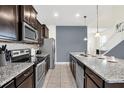 Modern kitchen with dark cabinets, granite counters, and stainless steel appliances at 1804 Gobi Dr, Kissimmee, FL 34747