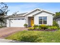 Curb appeal of a one-story house with gray siding, yellow door, and landscaped lawn at 7409 Wing Span Way, Harmony, FL 34773