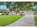 House with a lush green lawn and driveway, partially shaded by a large tree at 702 Valencia Shores Dr, Winter Garden, FL 34787