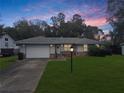 Ranch style home with attached garage and landscaped yard at dusk at 704 Monroe Harbor Pl, Sanford, FL 32773