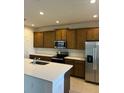 Modern kitchen with wood cabinets, white quartz countertops and stainless steel appliances at 1992 Heart Lake Dr, Groveland, FL 34736