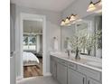 Double vanity bathroom with gray cabinets and a large mirror at 1104 Western Blue Way, Minneola, FL 34715