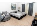 Spacious bedroom with large bed, plush seating, and neutral decor at 975 Benjamin Trl, Davenport, FL 33837