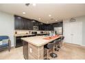 Kitchen island with seating, granite countertops, and dark wood cabinets at 975 Benjamin Trl, Davenport, FL 33837