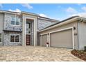 Modern house exterior with stone accents, three car garage, and paver driveway at 2205 Lake Sylvan Oaks Ct, Sanford, FL 32771