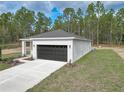 White house with a black garage door and landscaping at 406 Nw Narcissus Rd, Dunnellon, FL 34431