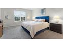 Bedroom with a blue upholstered bed, carpeted floor, and window with blinds at 12128 Illustration Dr, Orlando, FL 32832