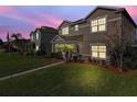 Two-story house with light brown exterior, landscaping and walkway at dusk at 1030 Bending Oak Trl, Winter Garden, FL 34787