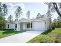 New single-story home with light beige siding, a two-car garage, and a covered porch at 245 Oak Lane Way, Ocala, FL 34472