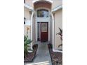 Inviting entryway with a burgundy door and landscaping at 7947 Golden Pond Cir, Kissimmee, FL 34747