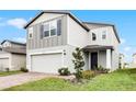 Two-story house with gray and white siding, brick driveway and landscaping at 4932 Mainsail St, Haines City, FL 33844
