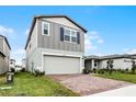 Two-story house with gray siding, brick driveway, and landscaping at 4932 Mainsail St, Haines City, FL 33844