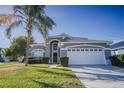 Two-story house with gray siding, white garage door, and palm tree in front at 2214 Wyndham Palms Way, Kissimmee, FL 34747