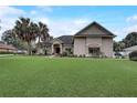 One-story house with large green lawn, palm trees, and a red front door at 4320 Se 106Th St, Belleview, FL 34420