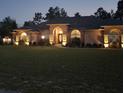 Well lit home with landscaping and large yard at dusk at 10411 Sw 52Nd Ct, Ocala, FL 34476