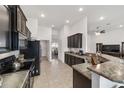 Modern kitchen with dark cabinetry, granite countertops, and black appliances at 3235 Se 43Rd Ave, Ocala, FL 34480