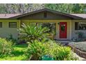 Mid-century modern home with red door and mature landscaping at 3751 Se 3Rd Ave, Ocala, FL 34471