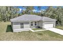 Newly constructed one-story home with gray siding, a white garage door, and a well-manicured lawn at 6839 Sw 149Th Lane Rd, Ocala, FL 34473