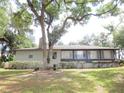 House rear view, showcasing a screened porch and lush greenery at 16789 Se 69Th Ln, Ocklawaha, FL 32179