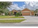 Tan two-story house with three car garage and landscaping at 9818 Sw 63Rd Loop, Ocala, FL 34481
