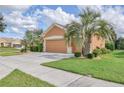Tan two-story house with three car garage and landscaping at 9818 Sw 63Rd Loop, Ocala, FL 34481