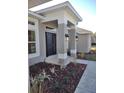Modern front entrance with a black door, columns, and decorative landscaping at 5508 Sw 108Th St, Ocala, FL 34476