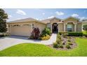 Tan one-story house with a two-car garage and a landscaped front yard with walkway at 15890 Sw 11Th Terrace Rd, Ocala, FL 34473