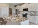 Modern kitchen with white cabinets, granite countertops, and stainless steel appliances at 3120 Canopy Oak Blvd, Wildwood, FL 34785