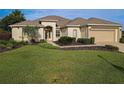 Tan colored house with a large yard and two-car garage at 9240 Se 128Th Ln, Summerfield, FL 34491