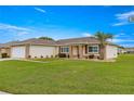 House exterior with a garage and landscaped lawn at 13811 Se 84Th Ct, Summerfield, FL 34491