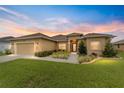 Tan one-story house with a two-car garage and landscaped yard at 10200 Se 67Th Ter, Belleview, FL 34420