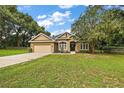 House exterior showcasing a tan stucco exterior, a two-car garage, and a manicured lawn at 9680 Ne 25Th Ct, Anthony, FL 32617