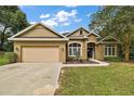 Tan stucco house exterior with a two-car garage and well-maintained landscaping at 9680 Ne 25Th Ct, Anthony, FL 32617
