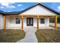 Charming front porch with wood columns, black double doors, and wood ceiling at 9065 Sw 121St Ter, Dunnellon, FL 34432