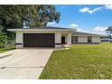 Modern home with a dark garage door, light-colored exterior, and a grassy yard at 6760 Cherry Rd, Ocala, FL 34472