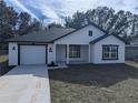 White house with black accents, gray roof, and driveway at 13060 Sw 113Th Pl, Dunnellon, FL 34432