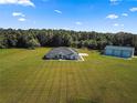 Aerial view of a house, detached garage, and expansive lawn at 5615 Nw 202Nd Pl, Mc Intosh, FL 32664