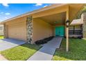 Home exterior featuring stone accents, a teal door, and a two-car garage at 4980 Sw 195Th Ave, Dunnellon, FL 34431