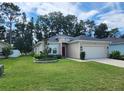Tan house with two car garage and manicured lawn at 7867 Sw 74Th Loop, Ocala, FL 34481