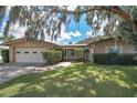 House exterior with a two-car garage and lawn at 12190 Maple St, Dunnellon, FL 34432