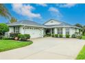 Light green house with a grey roof, white garage door, and landscaped yard at 15235 Sw 14Th Avenue Rd, Ocala, FL 34473