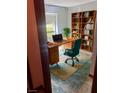 Virtually staged home office with built-in shelves and teal chair at 14323 Se 98Th Ave, Summerfield, FL 34491