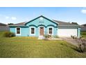 Newly built teal home with a two-car garage and lush green lawn at 2405 Sw 147Th Place Rd, Ocala, FL 34473