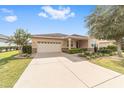 Tan house with a two-car garage and manicured landscaping at 9714 Sw 95Th Loop, Ocala, FL 34481