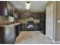 Modern kitchen with dark wood cabinets, black appliances, and tile flooring at 12321 Se 102Nd Ter, Belleview, FL 34420