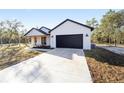 Modern farmhouse with white siding, dark garage door, and porch at 12180 Sw 88Th St, Dunnellon, FL 34432