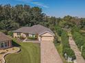 Single-story house with a tan exterior, brick driveway and landscaped yard at 13166 Se 86Th Cir, Summerfield, FL 34491